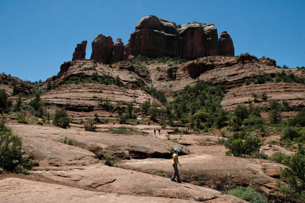 Looking up at Cathedrial Rock from part way up the Cathedral Rock Trail. Hikers can be seen making their way up the trail.